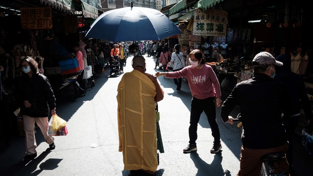 A woman offers a donation to a monk walking the streets of the Sanhe Market in Kaohsiung, Taiwan. (Yasuyoshi Chiba/AFP via Getty Images)